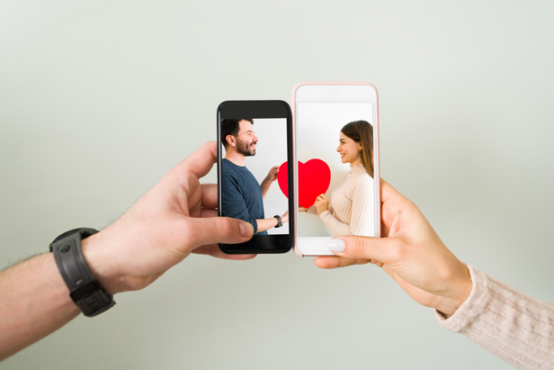 Two phones side by side, displaying a couple holding a heart between them